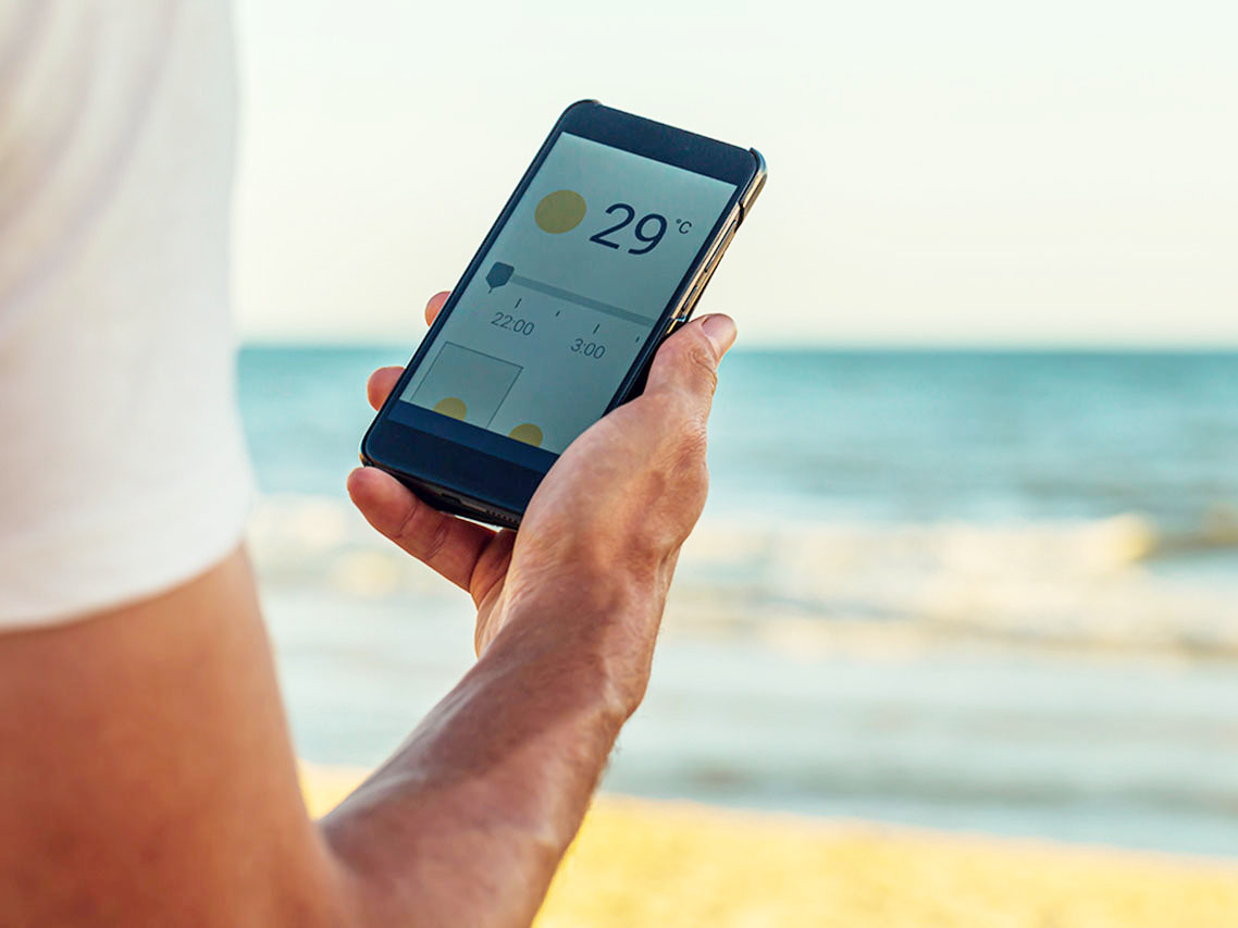 Smart phone with weather forecast on screen, smart phone dialing 29ºC at Matalascañas beach in Huelva, Andalusia, Spain